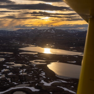 Vertical view of a vibrant sunset from the window of a small bush plane in Southwest Alaska